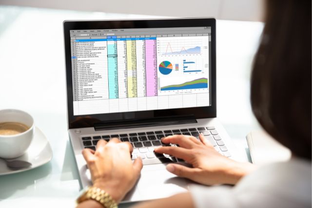 A woman sitting at a laptop, looking at her website content to see if it's time to perform a content audit.